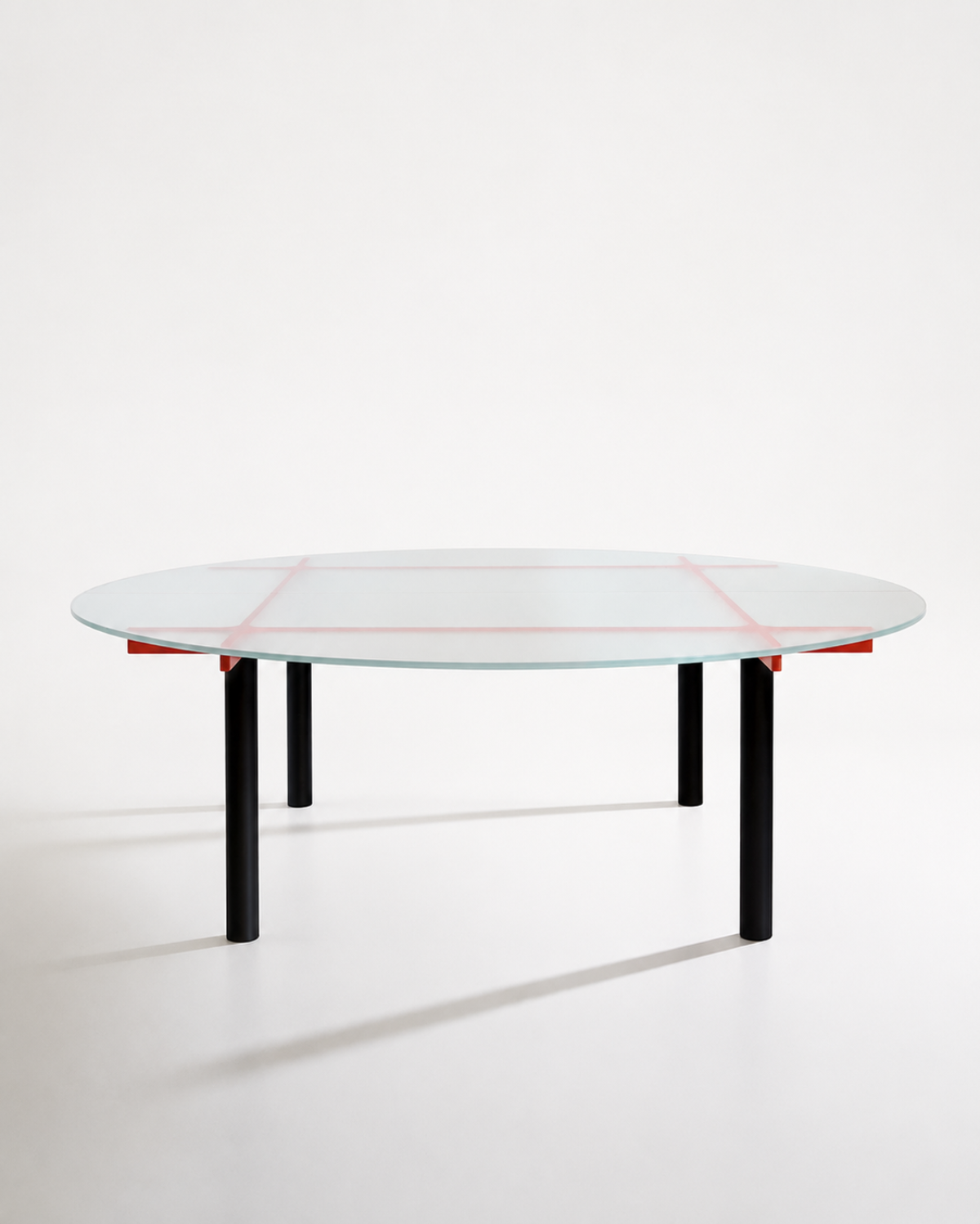 A modern round glass-top table with a black metal frame and four legs, accented by thin red lines on the glass and small red brackets under the rim, shown on a clean white studio background.
