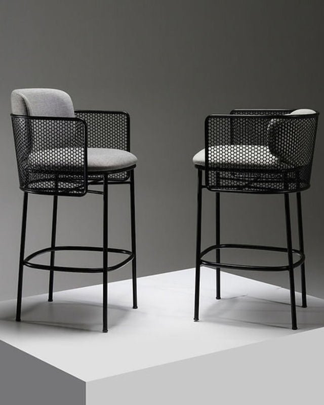 Two black bar stools with woven backrests and white cushioned seats on a gray background.