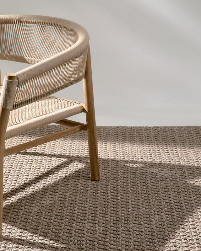 Wicker chair on a textured beige carpet with a neutral background