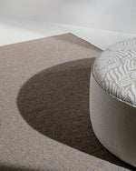 Textured rug with a patterned ottoman on a neutral background