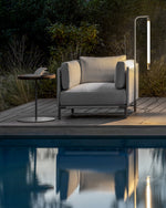 Baia lamp outdoors next to a one seater couch.