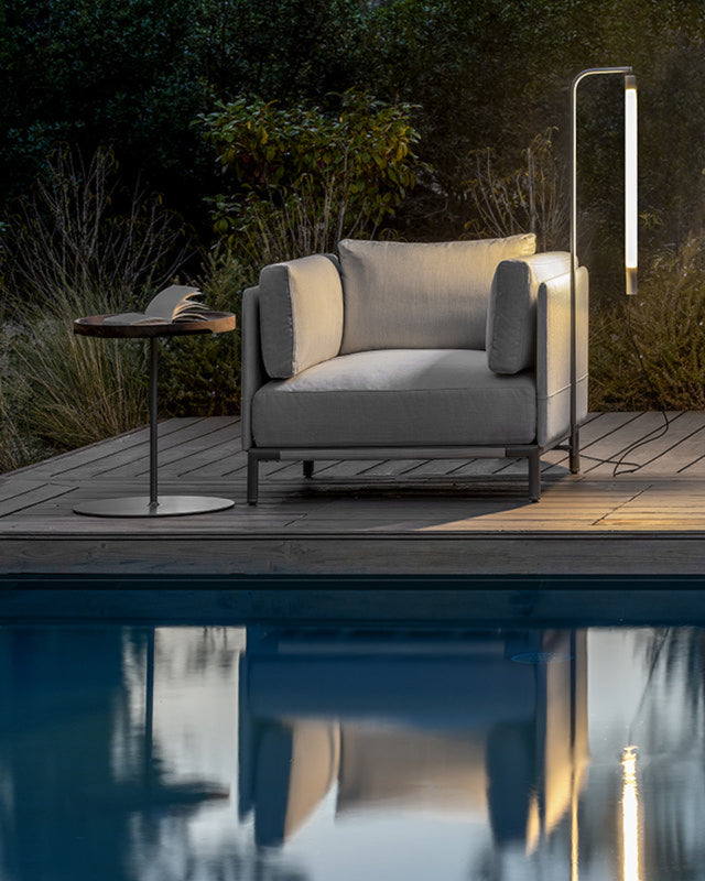 Baia lamp outdoors next to a one seater couch.