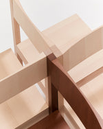 Close-up of a wooden furniture corner showing light natural wood and darker reddish-brown wood pieces joined together with a visible mortise and tenon joint.