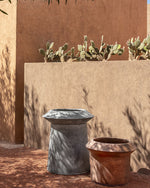 Two outdoor planters with cacti against a textured wall.
