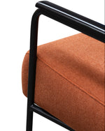 Close-up of an orange upholstered chair with black metal frame on a white background
