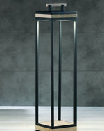 Carre XL Floor Lamp in pickled teak and aluminium textured matt sepia black in a dark room with tiles as walls.