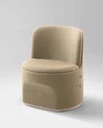 A modern low-profile accent chair upholstered in a textured beige fabric, featuring a rounded backrest and a sculptural base with two small side buttons, set against a neutral gray studio background.