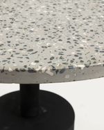 Close-up of a terrazzo-style table top with a speckled pattern on a white background.