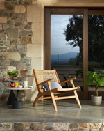 Wooden chair on a stone patio with a scenic view through a large window.