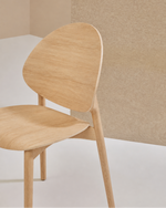 A light natural wood dining chair with a curved backrest and seat, shown against a minimalist beige and white background.