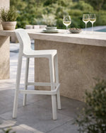 White bar stool in an outdoor setting with a table and glasses.