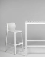 White bar stool and table against a gray background