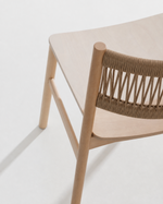 Close-up of a light natural wood dining chair with a woven rope backrest on a clean white background.