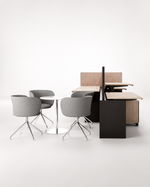A modern office furniture set featuring gray upholstered swivel chairs, a small round white table, light wood desks, and dark panel dividers on a clean white studio background.