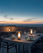 Lucerna Outdoor Lamps on a table, lighting up the dinner table.