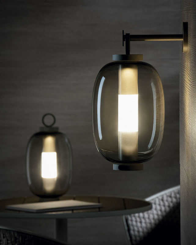 Lucerna Suspension Lamp in a restaurant, hanging from a wall, with a Lucerna Outdoor Lamp on the table in the background.
