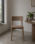Wooden chair in a minimalistic room with a table and plants.