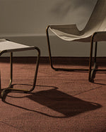 Chair and ottoman on a textured brown floor with a neutral wall background