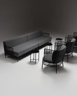 Modern gray sofa and black chairs on a dark background