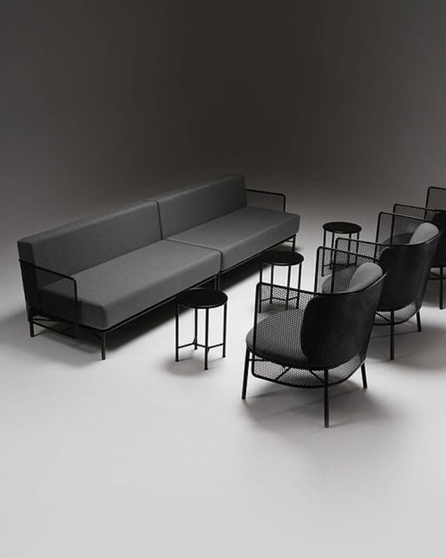 Modern gray sofa and black chairs on a dark background