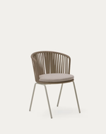 A modern outdoor accent chair with a curved backrest made of vertical wicker slats, a light beige cushioned seat, and slim gray metal legs, shown against a solid off-white background.