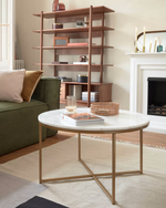 Living room with a round marble table, green sofa, and wooden shelf.