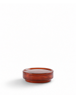 A small round amber-brown translucent glass dish or candle holder with a smooth glossy finish, set against a solid white background.