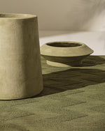 Two concrete planters on a textured surface with a neutral background