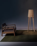 Woody floor lamp on top of a tetide rug, lighting up the underneath of the lamp and its surrounding areas.