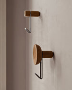 Close-up showing black hook and concave walnut back of Around wall hanger.