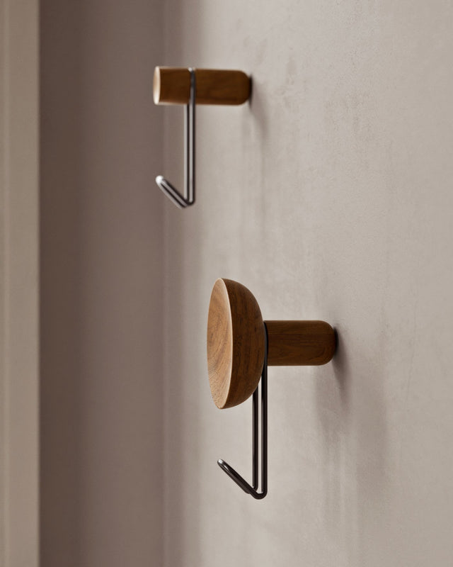 Close-up showing black hook and concave walnut back of Around wall hanger.
