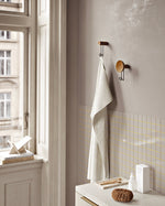 Profile view of Around wall hanger showing wooden concave plate and metal hook.