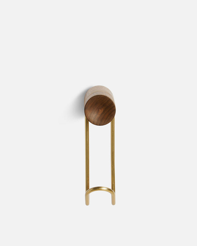 Close-up showing satin brass hook and concave walnut back of Around wall hanger.