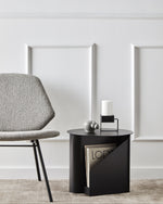 Side view of Sentrum Side Table showing its S-shaped frame and two open magazine slots.